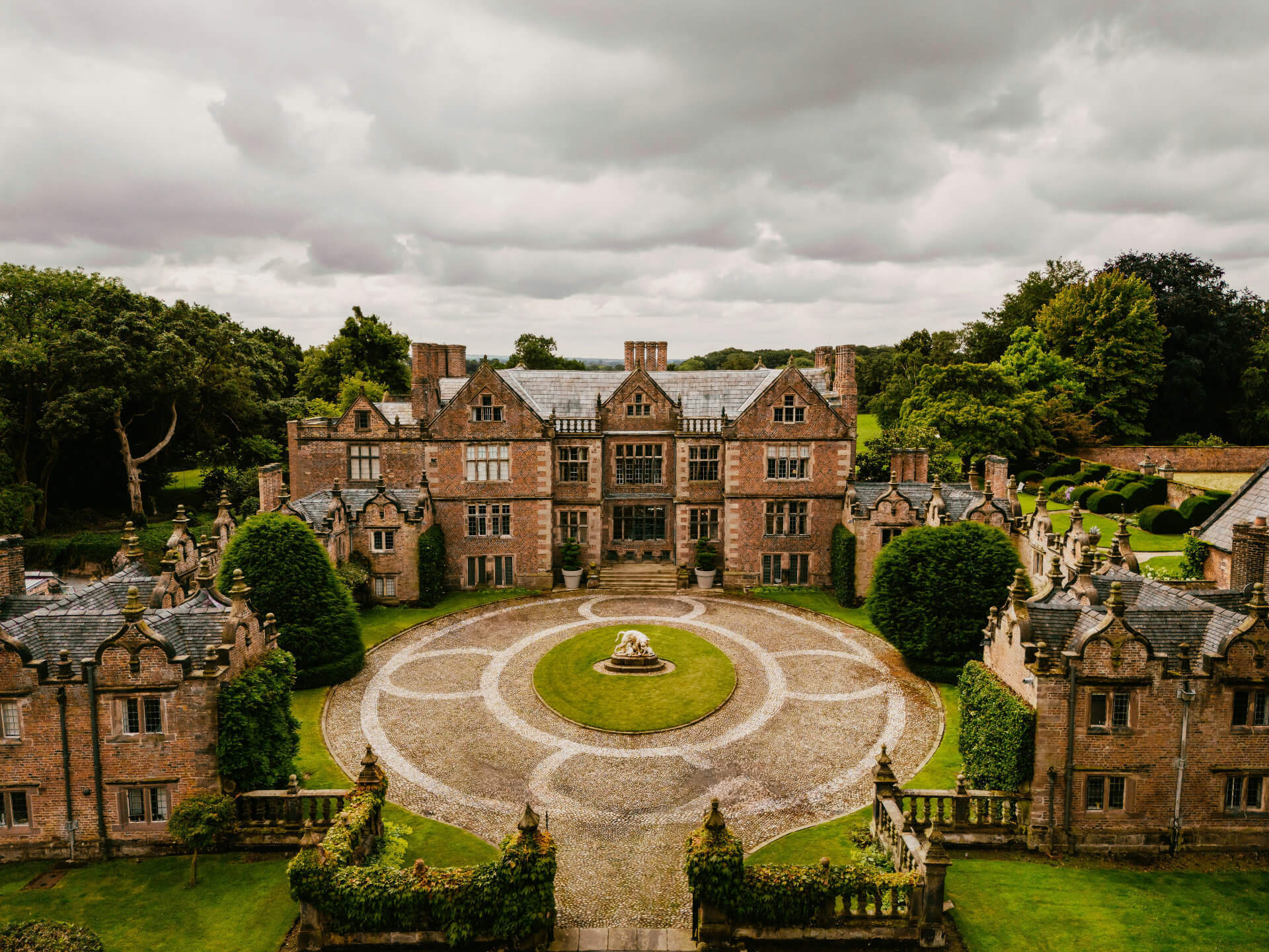 An English stately home with a circular cobbled courtyard and lawn